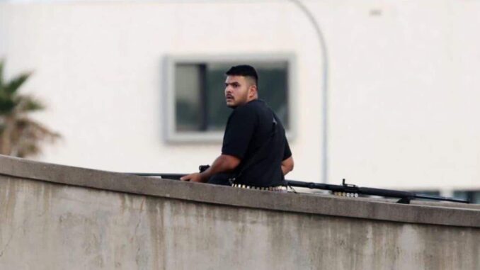 Man standing on rooftop with a rifle.