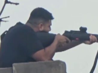 Person aiming rifle from a rooftop.