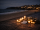 Candles and flowers by the beachside at night.