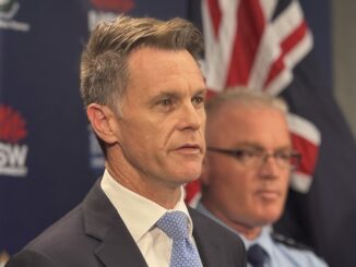 Suit-clad man speaking beside uniformed officer