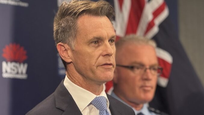 Suit-clad man speaking beside uniformed officer Suit-clad man speaking beside uniformed officer
