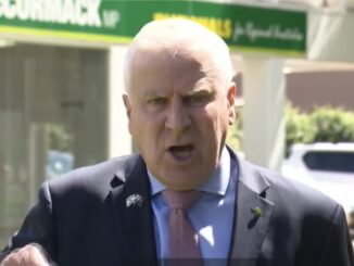 Man speaking outdoors near a building sign.