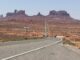 Desert road leading to distant rock formations.