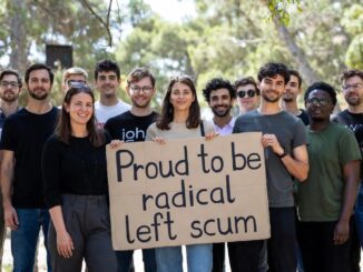 Group holding sign outdoors, smiling together.