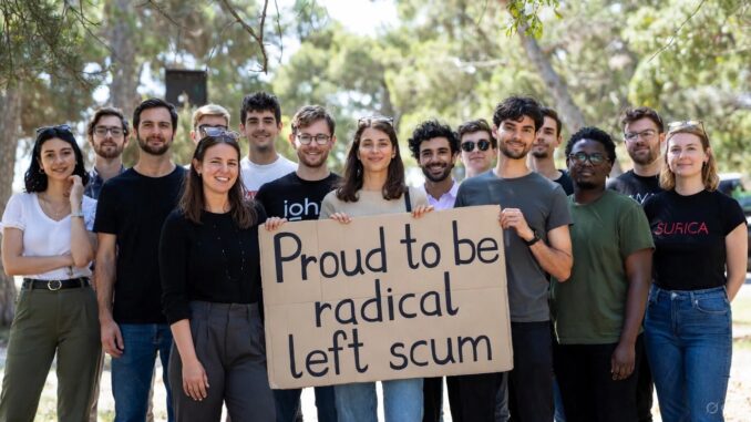 Group holding sign outdoors, smiling together. Group holding sign outdoors, smiling together.
