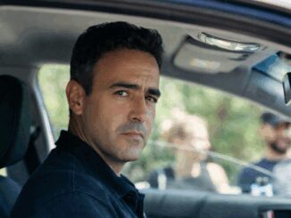 Man sitting in car, looking serious outside.