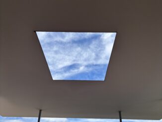 Ceiling skylight framing blue sky view.