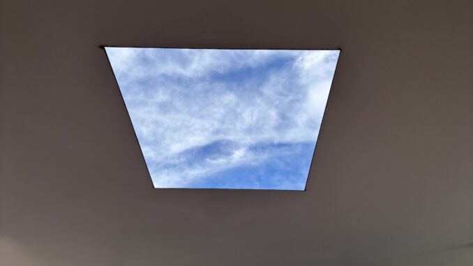 Ceiling skylight framing blue sky view.