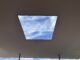 Ceiling skylight framing blue sky view.