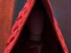 Red hooded figure with quilted garment.