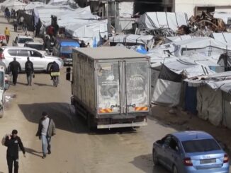 Street with vehicles and tents, crowded scene.
