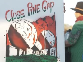 Protest sign reading "Close Pine Gap" held.