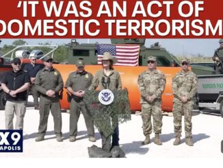 Officials standing in front of military vehicles.