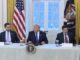 Meeting at a table with officials present.