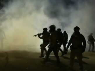 Silhouetted figures in smoke-filled nighttime scene.