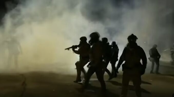 Silhouetted figures in smoke-filled nighttime scene.