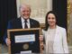 Two people holding a framed award certificate.