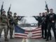Soldiers and ICE agents holding damaged flag.