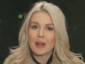 Person with long blonde hair speaking outdoors.