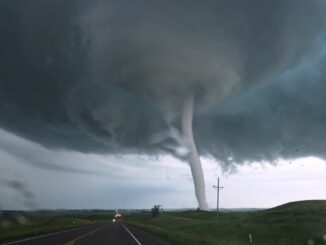 Tornado touching down near open road.