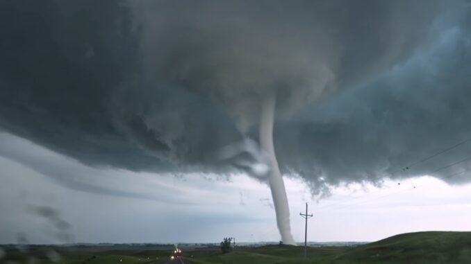 Tornado touching down near open road.