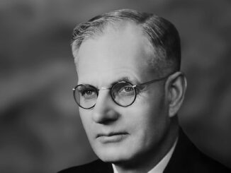 Man wearing glasses, suit, and tie portrait.