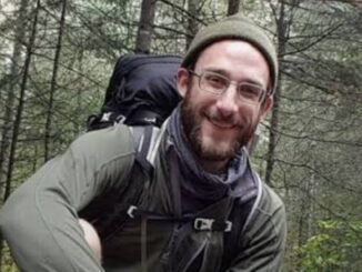 Smiling hiker in forest with backpack.
