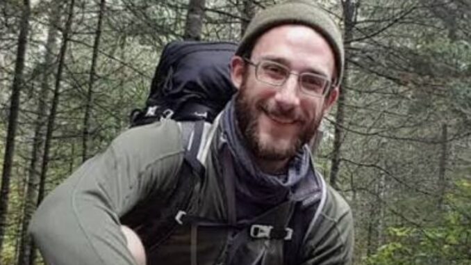 Smiling hiker in forest with backpack.