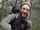 Smiling hiker in forest with backpack.