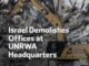 Excavator demolishing UNRWA headquarters building rubble.