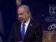 Man speaking at a podium, Israeli flag background.