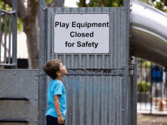 Child looking at closed playground sign.