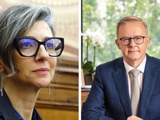 Two people wearing glasses in formal attire.