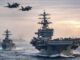 Aircraft carrier and jets at sea.