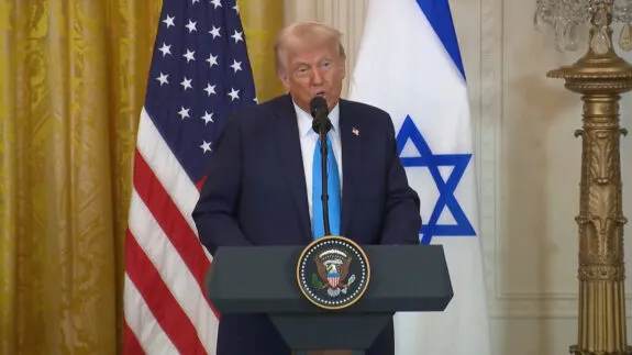Man speaking at podium with two flags. Man speaking at podium with two flags.
