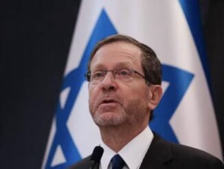 Man speaking in front of Israeli flag.