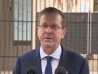 Man speaking at a podium outdoors.