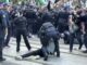 Police arresting protester during crowded demonstration.