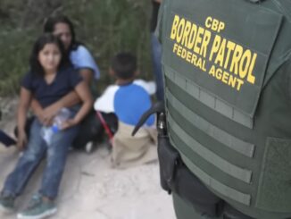 Border patrol agent with seated family nearby.