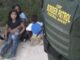Border patrol agent with seated family nearby.