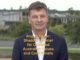 Man in suit with critical text overlay.