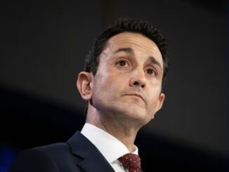Man in suit looking upwards, serious expression.