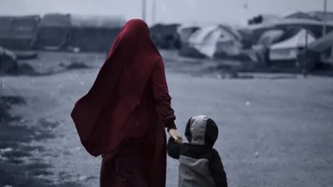 Woman and child walking through refugee camp.
