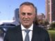News interviewee in suit with riverside skyline