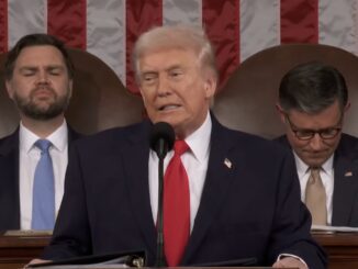 Man speaking at podium with audience behind.