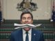 Man balancing metal leg in government chamber.