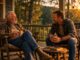 Two men talking on a porch.