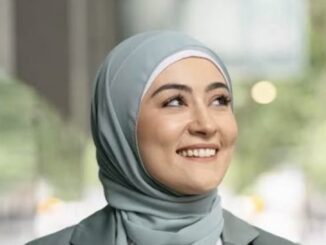 Smiling woman wearing a light blue hijab.