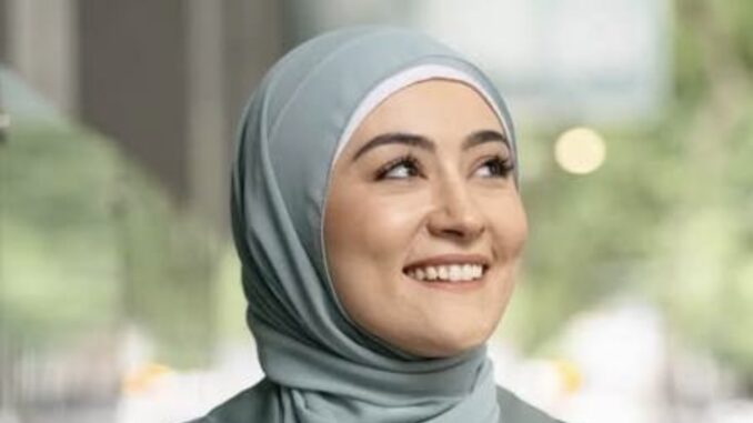 Smiling woman wearing a light blue hijab.