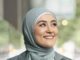 Smiling woman wearing a light blue hijab.